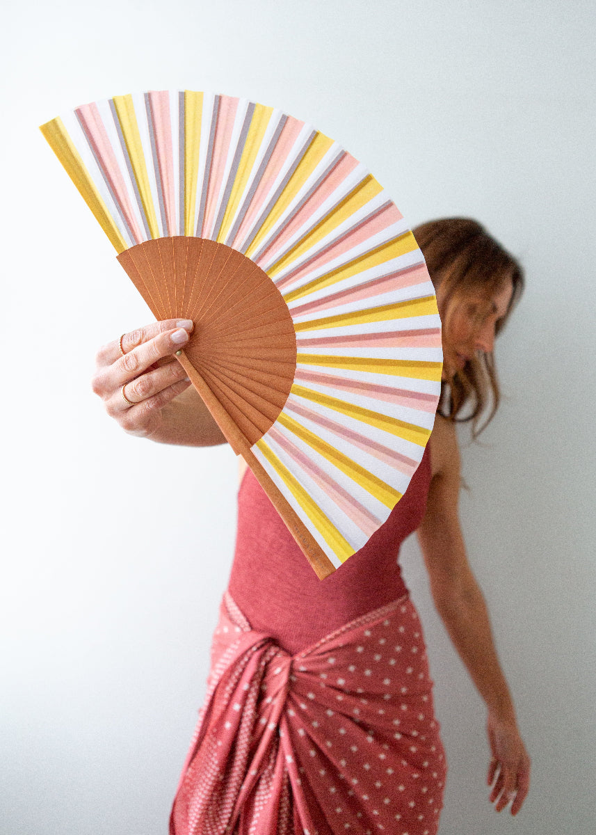 Person holding a colorful striped fan against a plain background