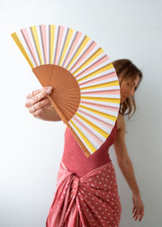 Person holding a colorful striped fan against a plain background