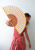 Person holding a colorful striped fan against a plain background