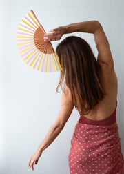 Woman holding a colorful hand fan against a plain background