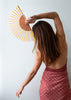 Woman holding a colorful hand fan against a plain background