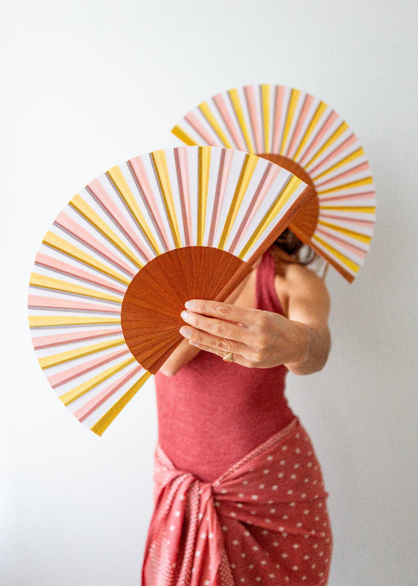 Person holding a colorful striped fan against a plain background