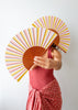 Person holding a colorful striped fan against a plain background