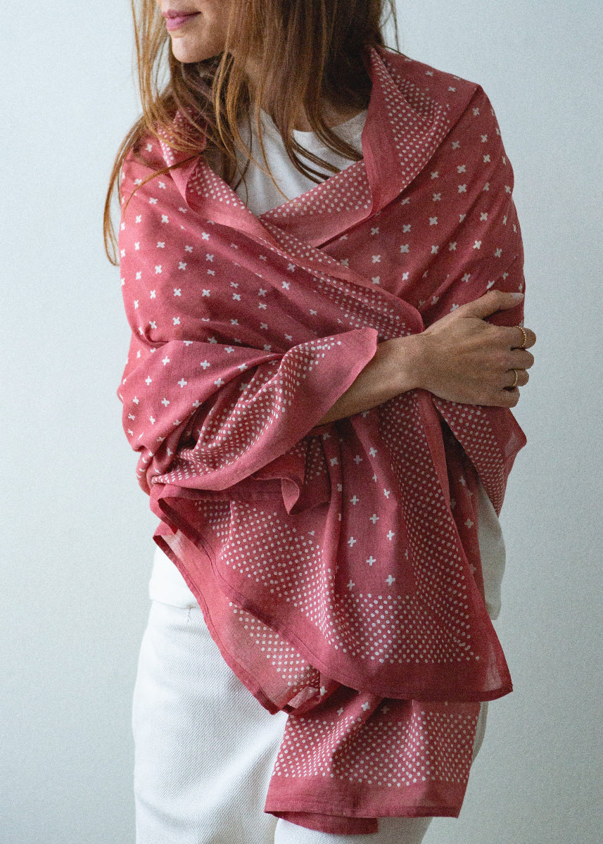 Person wearing a pink patterned scarf against a plain background