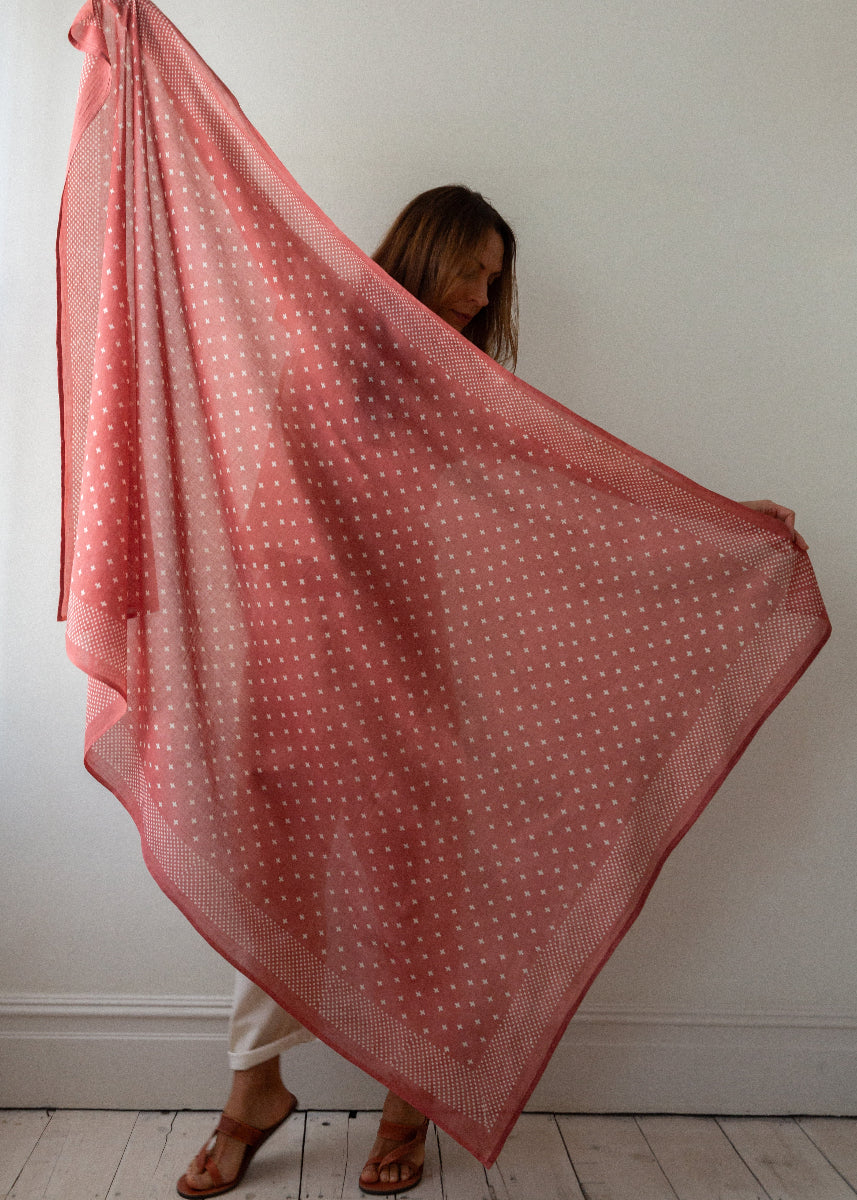 Person holding a pink polka dot scarf against a white wall