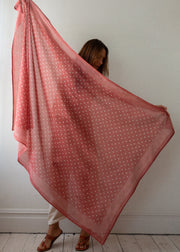Person holding a pink polka dot scarf against a white wall