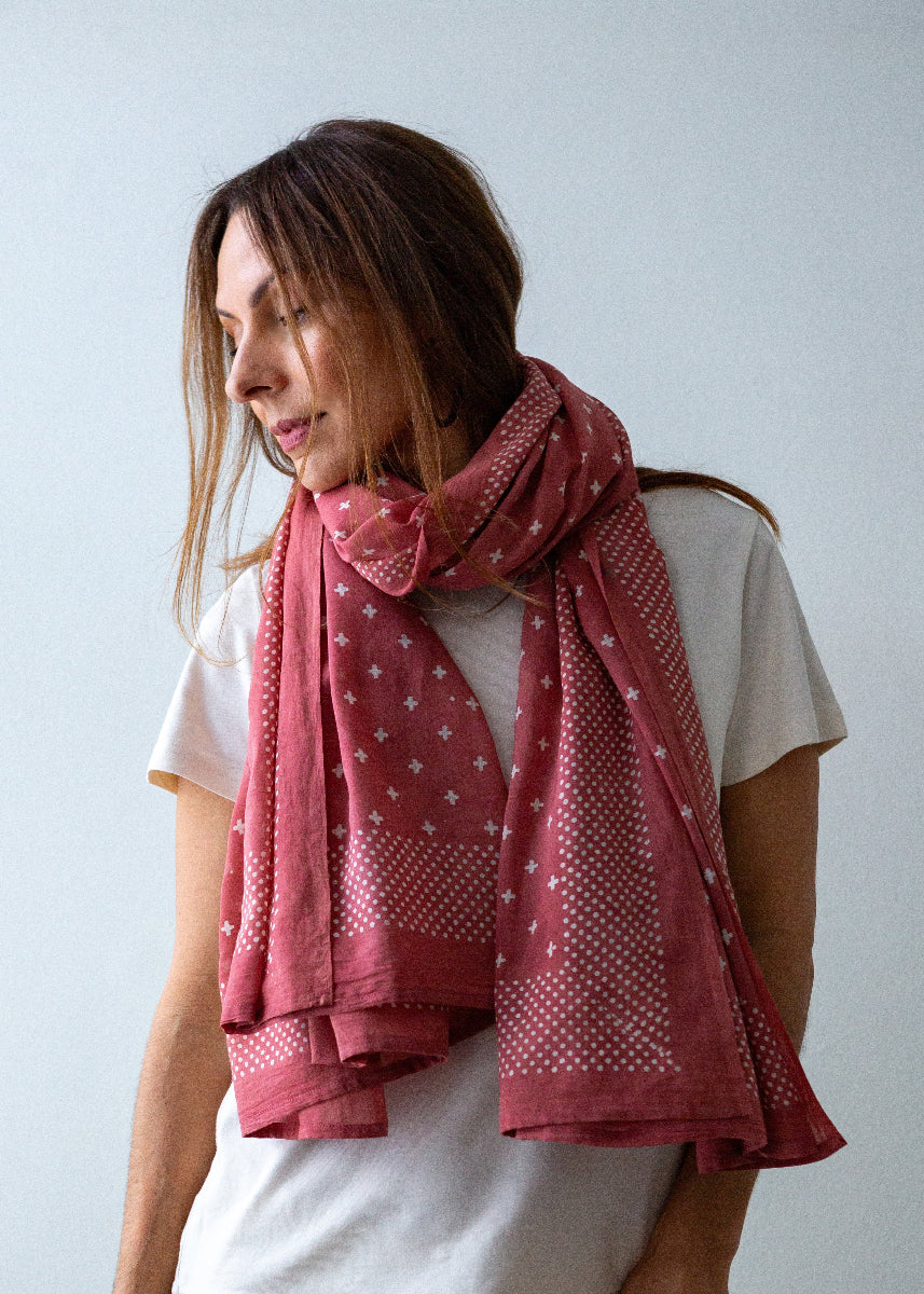 Woman wearing a pink patterned scarf on a plain background