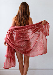 Woman holding a red polka dot scarf against a white background