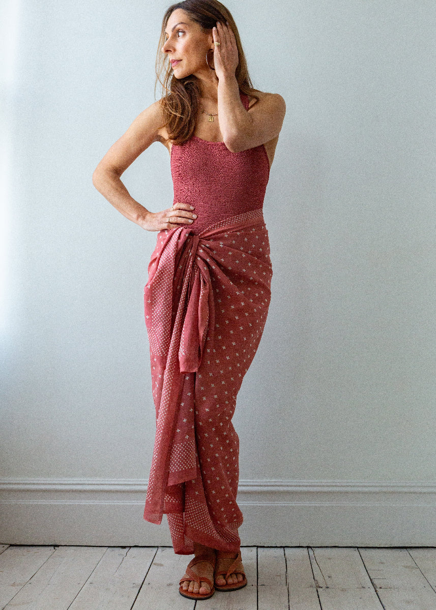 Woman wearing a pink sarong against a white wall