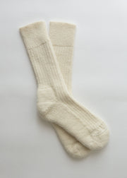 A pair of cream-colored ribbed knit crew alpaca socks laid flat on a light gray background.