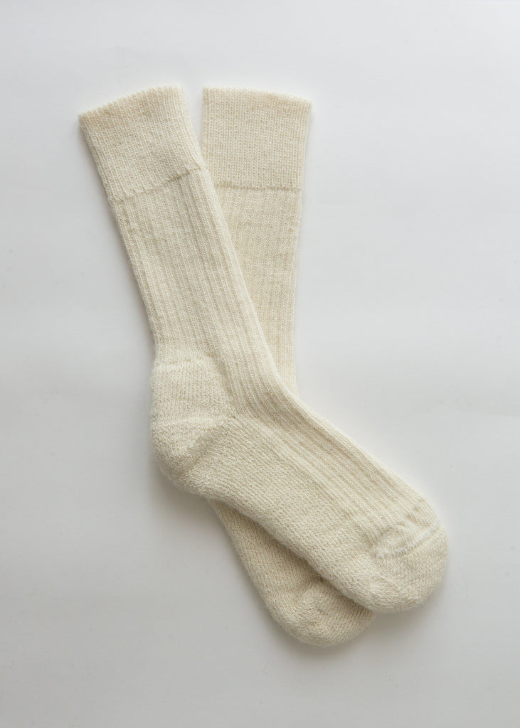 A pair of cream-colored ribbed knit crew alpaca socks laid flat on a light gray background.