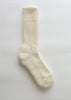 A single cream-colored ribbed knit alpaca sock displayed vertically against a clean, light off-white background.