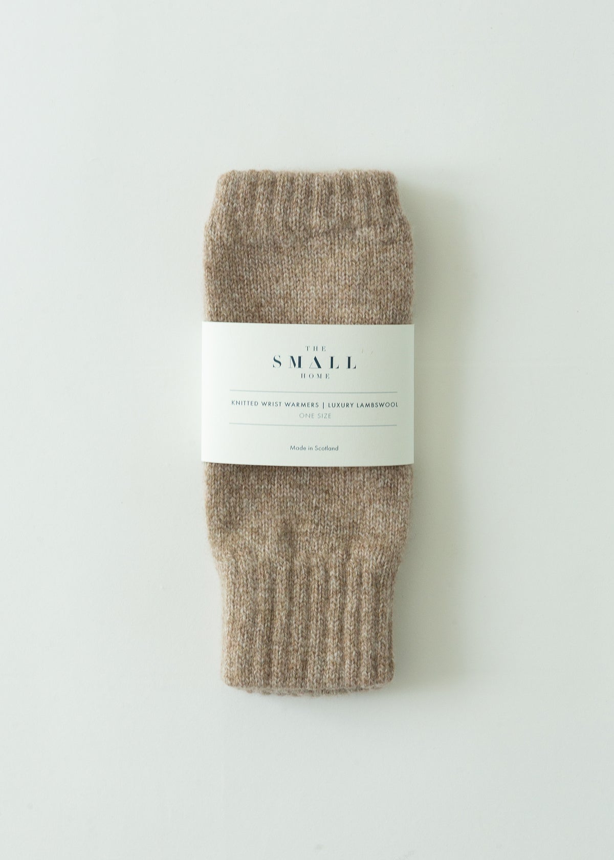 A pair of folded ribbed knit socks in a heathered taupe-brown color, wrapped with a white paper label that reads 'THE SMALL HOME'. The product is photographed flat on a clean, light off-white background.