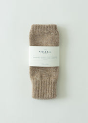 A pair of folded ribbed knit socks in a heathered taupe-brown color, wrapped with a white paper label that reads 'THE SMALL HOME'. The product is photographed flat on a clean, light off-white background.