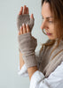 A woman wearing beige knit fingerless gloves and a matching knit sweater vest, shown from the side against a plain light gray background.