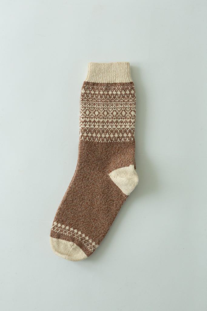 A single brown knit sock with cream-colored toe, heel, and cuff details, featuring a cream and brown geometric pattern around the calf, laid flat on a light gray background.