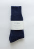 A pair of dark navy blue ribbed knit alpaca socks bundled with a white paper label that reads 'THE SMALL HOUSE'.