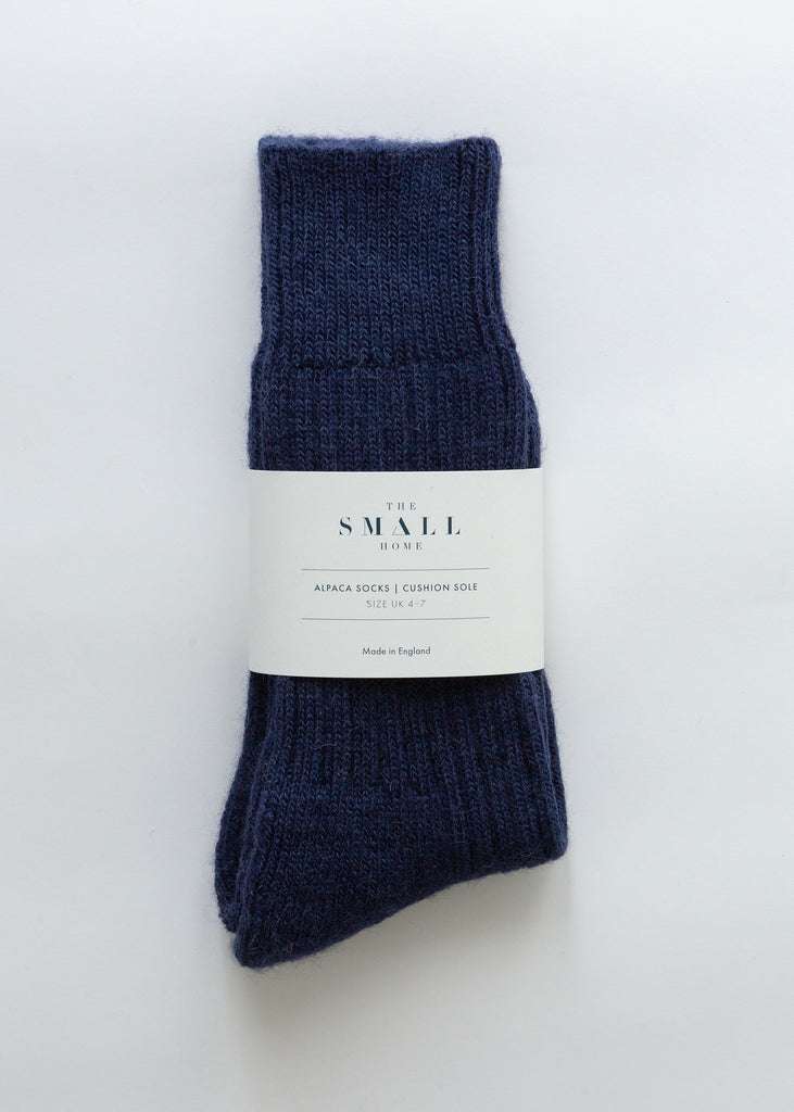 A pair of dark navy blue ribbed knit alpaca socks bundled with a white paper label that reads 'THE SMALL HOUSE'.