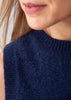 Close-up of a person wearing a dark navy blue knit sleeveless top or sweater, showing the ribbed crew neck and textured fabric.