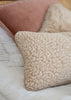 Two textured merino wool cushions in cream on a bed with a matching wool bedspread