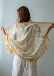 Person wearing a colorful scarf with grid pattern on a plain background