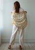 Person holding a colorful checkered scarf in a minimalistic room.
