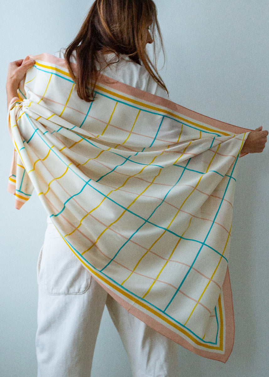 Person holding a colorful grid-patterned scarf against a plain background