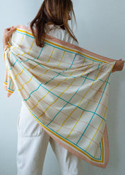 Person holding a colorful grid-patterned scarf against a plain background