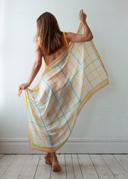 Woman holding a large checkered sarongagainst a white wall