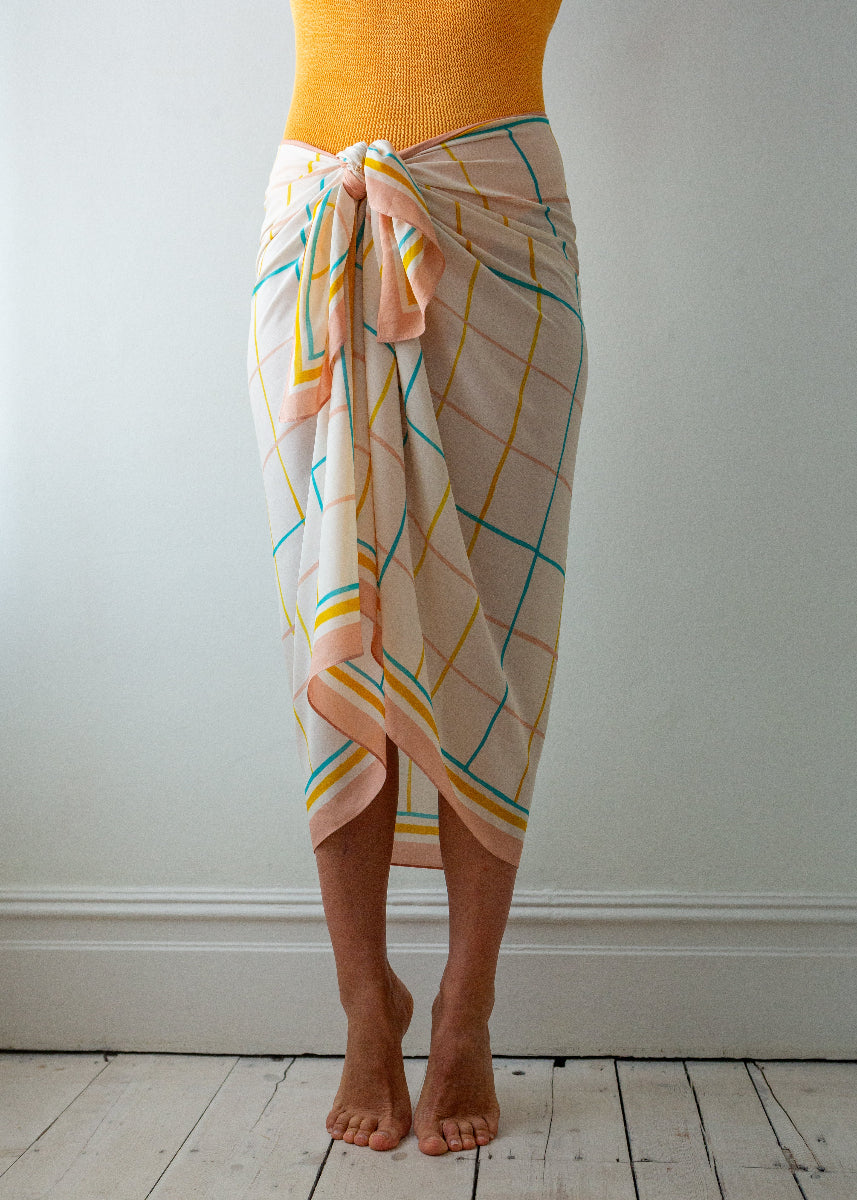 Person wearing a colorful grid-patterned wrap over a yellow top on a white background