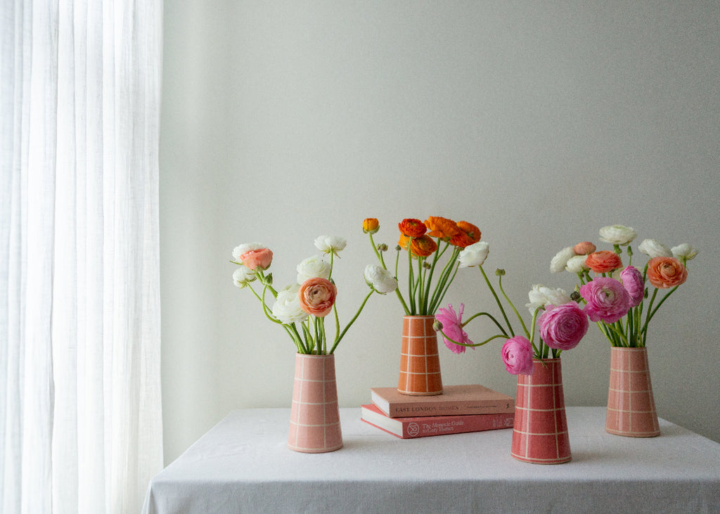 orange handmade vase with grid pattern and orange flowers