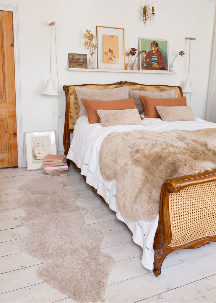 Double oatmeal shearling rug on floor next to a bed