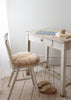 Small wooden desk with a chair and footstool in a room with white walls and wooden floor.