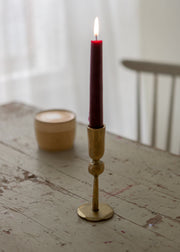 Candle in a brass holder on a wooden surface with a blurred background