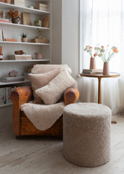 short wool curly sheepskin rug in an oatmeal colour over a leather chair