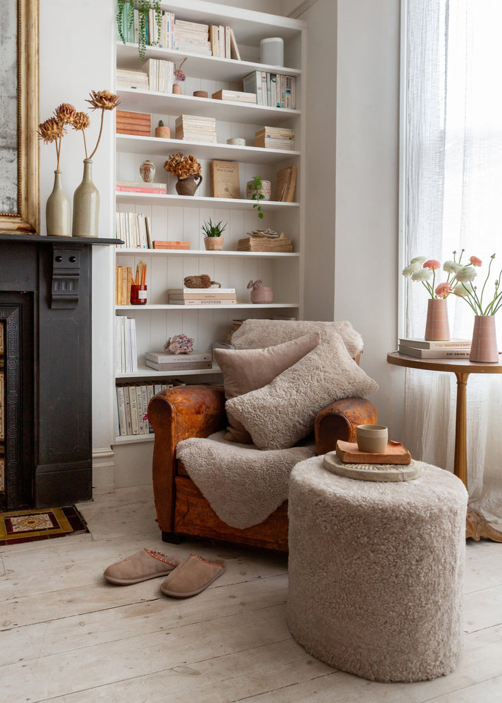 Cozy living room with a brown armchair, ottoman, and bookshelf.