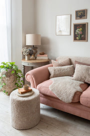 Cozy living room with a pink sofa, ottoman, and side table.