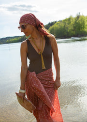 Woman in a swimsuit with a red headscarf and polka dot skirt by a lake