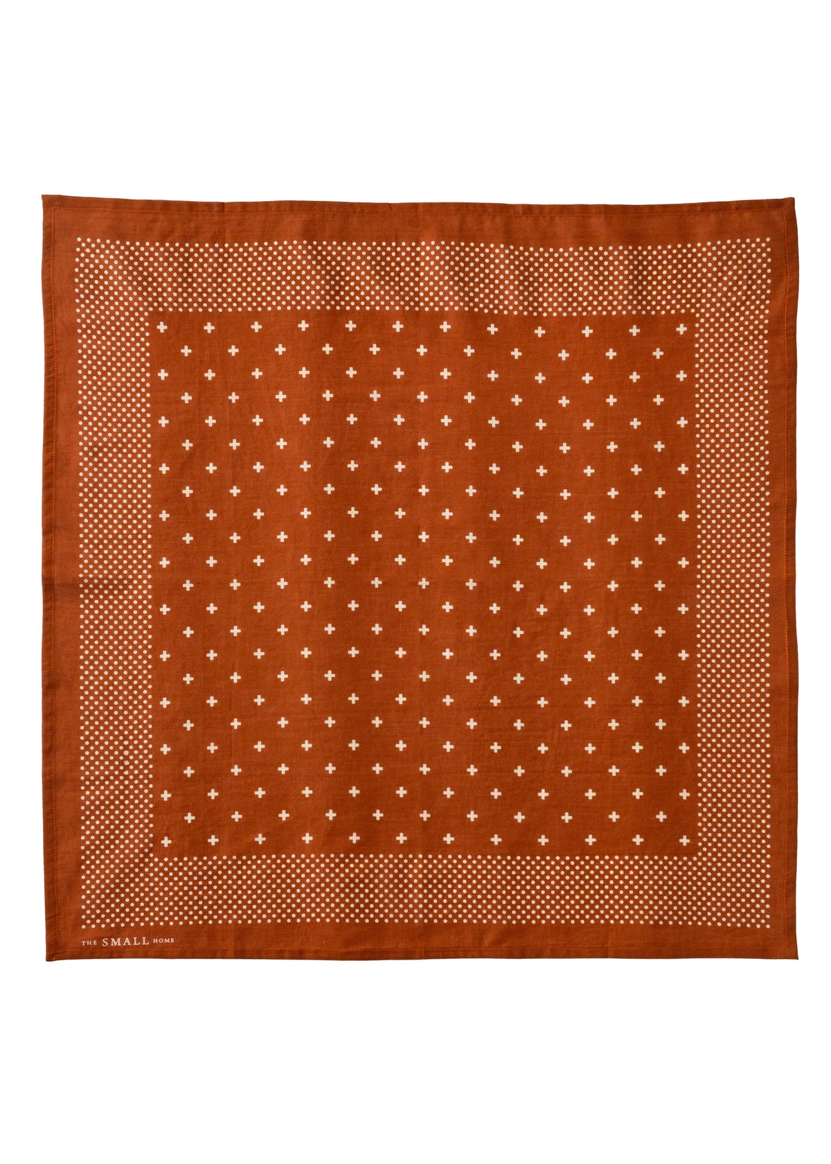 A square terracotta orange silk scarf with a white geometric pattern, featuring a central field of small white diamond motifs and a dotted border, shown flat against a white background.