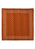 A square terracotta orange silk scarf with a white geometric pattern, featuring a central field of small white diamond motifs and a dotted border, shown flat against a white background.