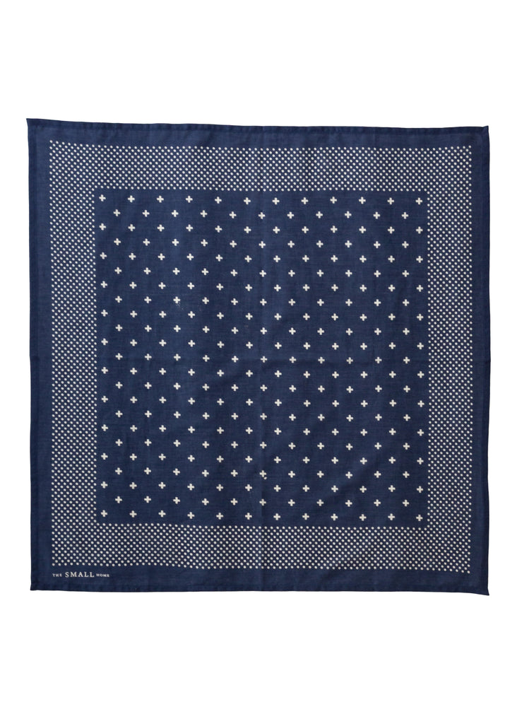 A square navy blue silk scarf with a white geometric pattern, featuring a central field of small white stars and a dotted border, laid flat on a white background.