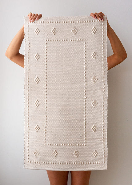 Hand-woven cotton rag bath mat in milk with chunky knotted texture made in Portugal